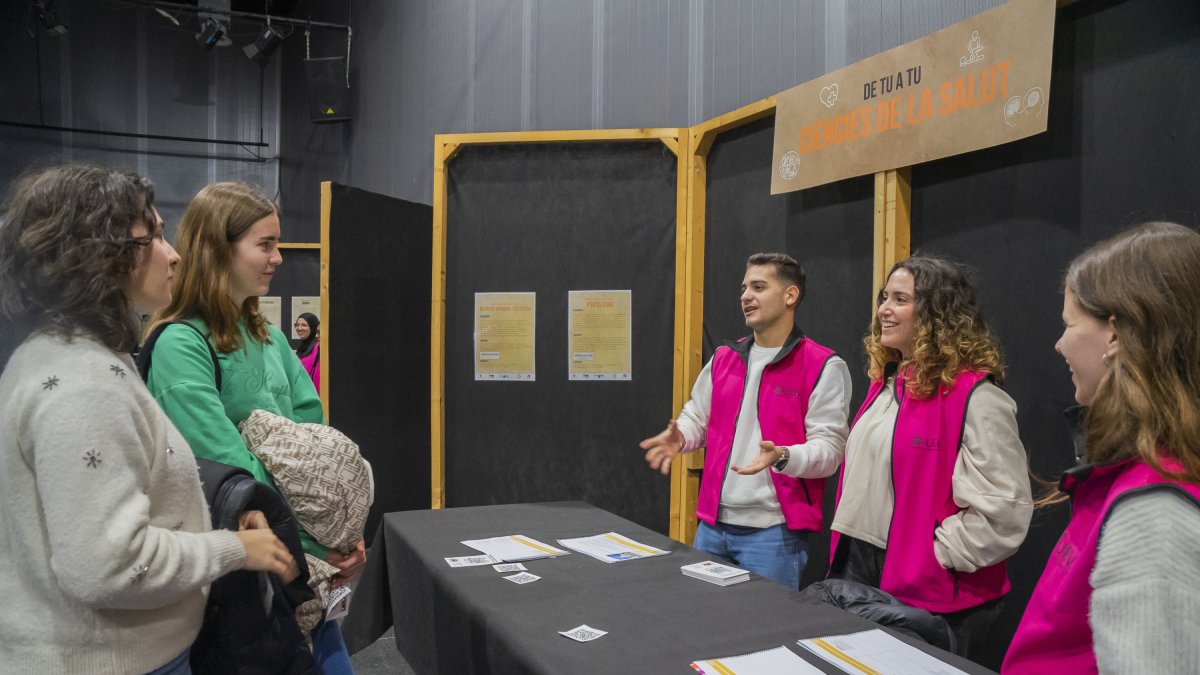Fotografía de jóvenes informándose en el estand de ciencias de la salud de la jornada 'de Tu a Tu'.