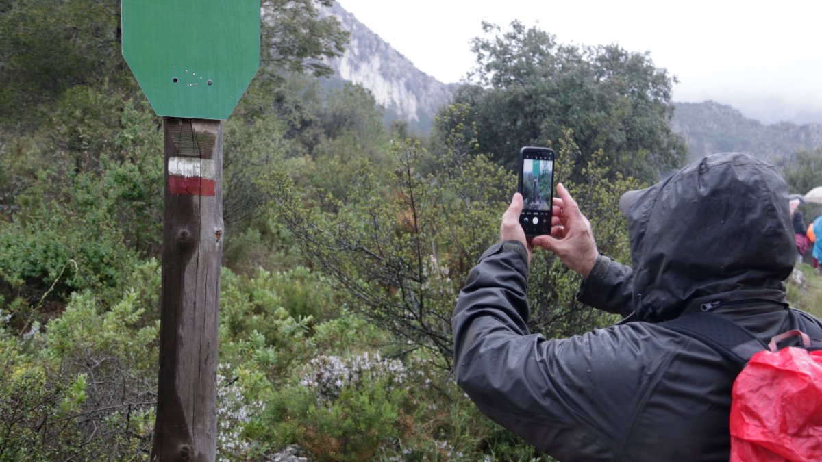 Un home fotografia una de les marques GR al sender que porta fins a l'ermita de Sant Blai a Tivissa