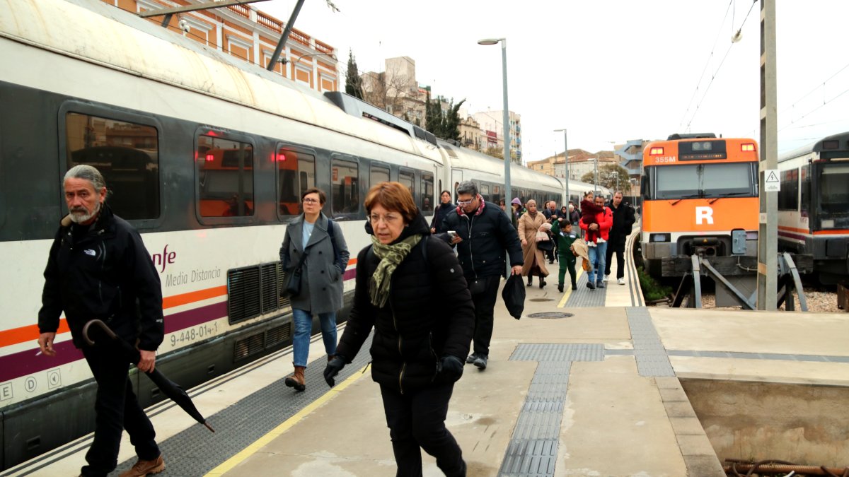 Usuaris sortint amb pressa d'un tren que ha arribat mitja hora tard a l'estació de Tortosa.