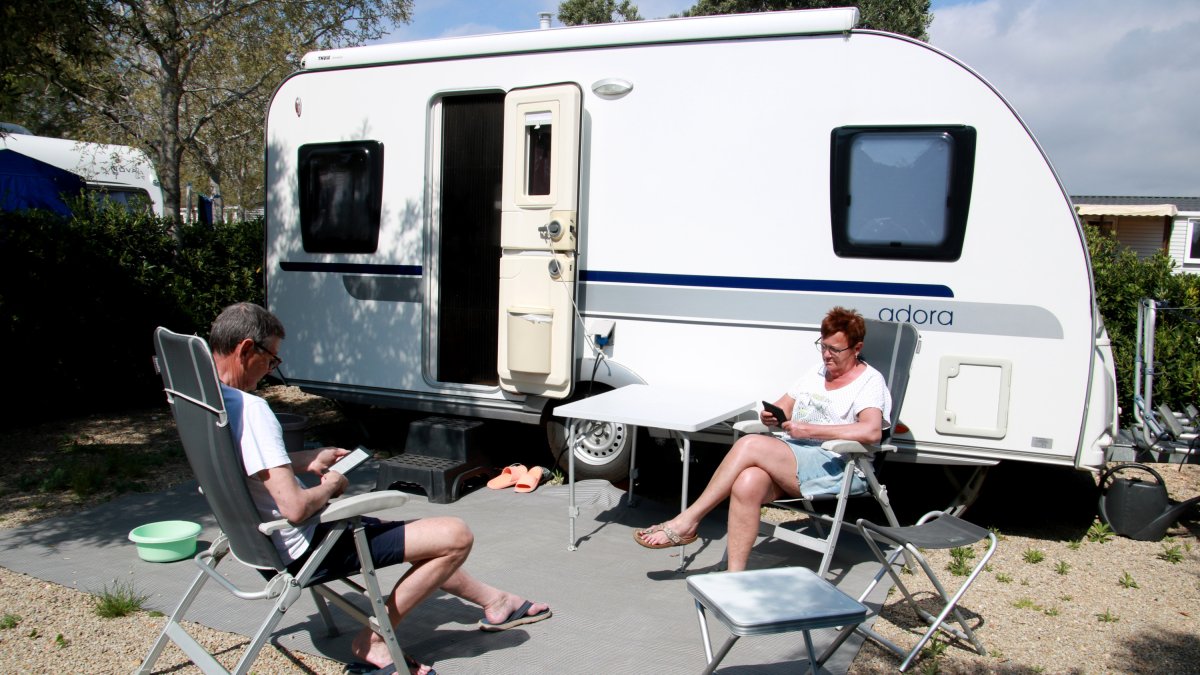 Dos turistes holandesos llegint al càmping Ametlla de l'Ametlla de Mar els dies prèvis a Setmana Santa.