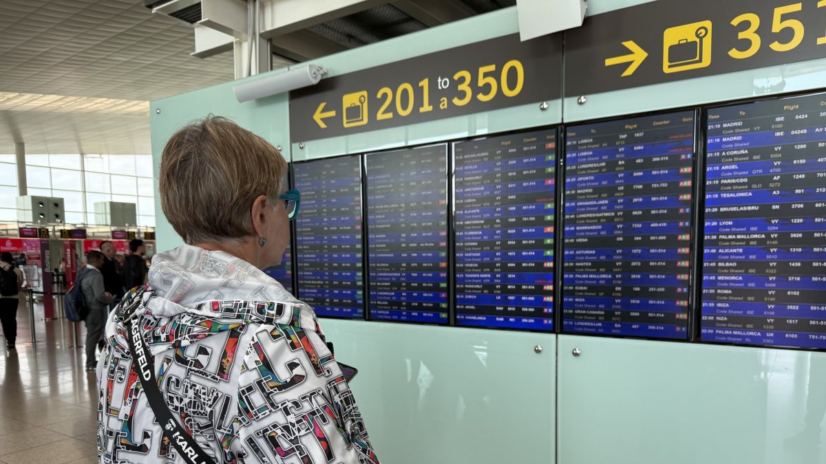 Una persona mira un par informativo en el aeropuerto del Prat durante un apagón eléctrico general.