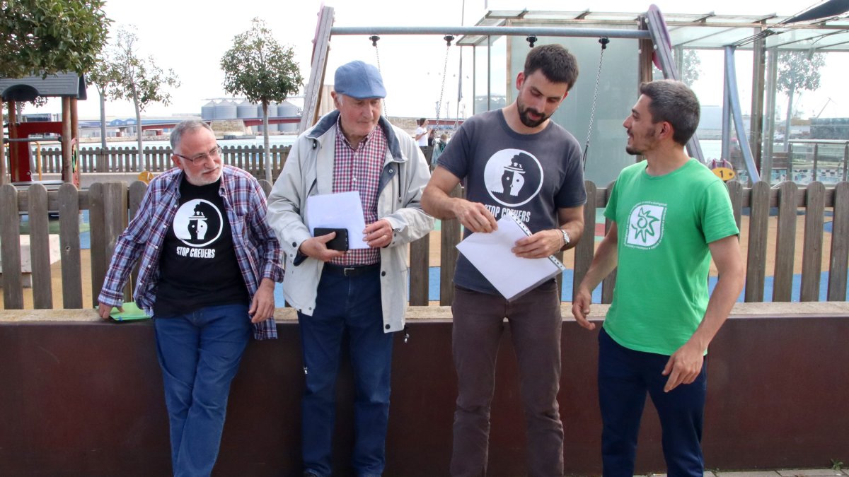 Membres d'Stop Creuers Tarragona revisen l'informe davant d'un parc infantil del port de Tarragona on es van prendre mostres.