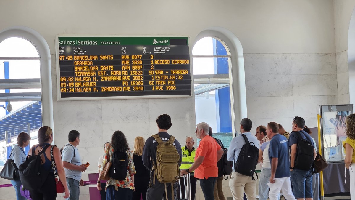 Usuarios observando un panel informativo en la estación de Lleida.