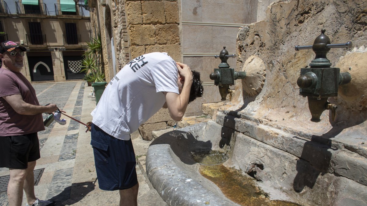 Un jove es refresca en una de les fonts de les escales de la catedral de Tarragona buscant alleujar les altes temperatures.