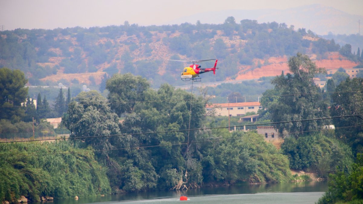 Un helicòpter d'extinció agafa aigua al riu Ebre, davant de Xerta.