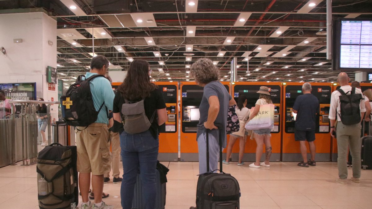 Personas esperando para utilizar una máquina de venta de billetes a la estación de Sants