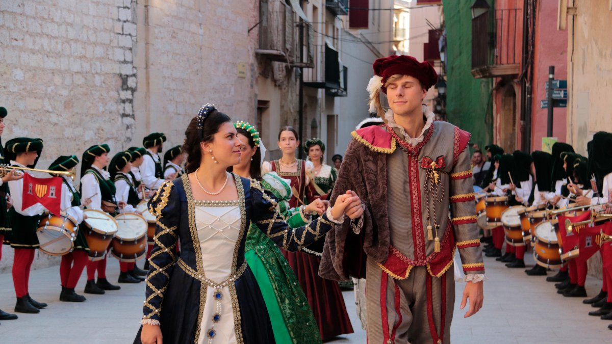 Una pareja participando en la entrega de estandards de las familias nobles de la Fiesta del Renaixament se miran mientras se dirigen a los Reals Col·legis de Tortosa.