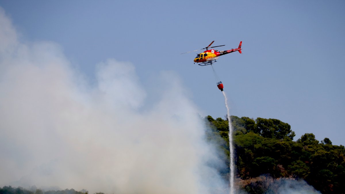 Un helicóptero descarga agua en un incendio forestal en Alforja.