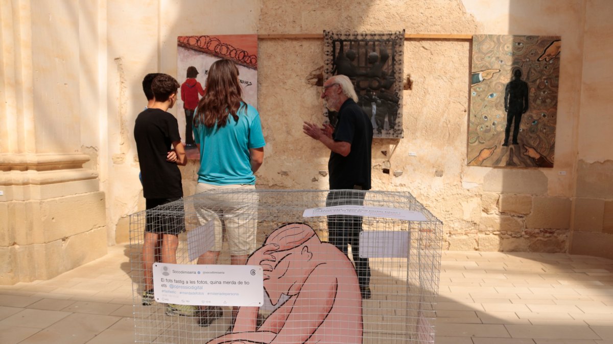 En Pere, el Gabriel i en Lori, tres joves de Corbera d'Ebre, escolten les explicacions de comissari de la Biennal d'Art de Corbera d'Ebre, Josep Canyadas