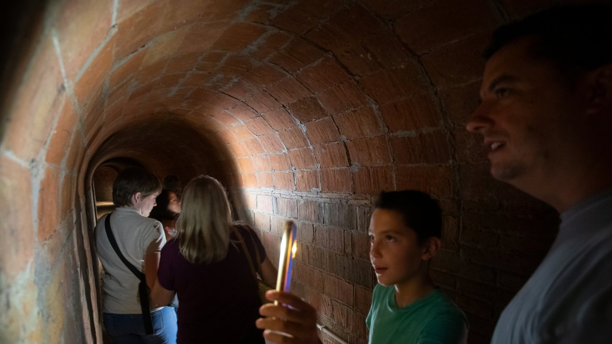 Visitants llegint missatges escrits a les parets del refugi antiaeri de la Patacada.