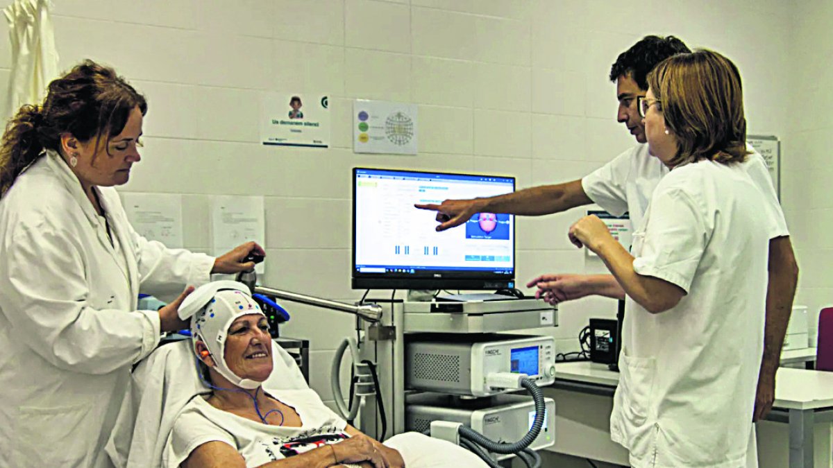 Vicenç Pascual, coordinador del servicio de Neurofisiología Clínica del HUSJR, junto con una paciente que se somete a la terapia para el dolor crónico.