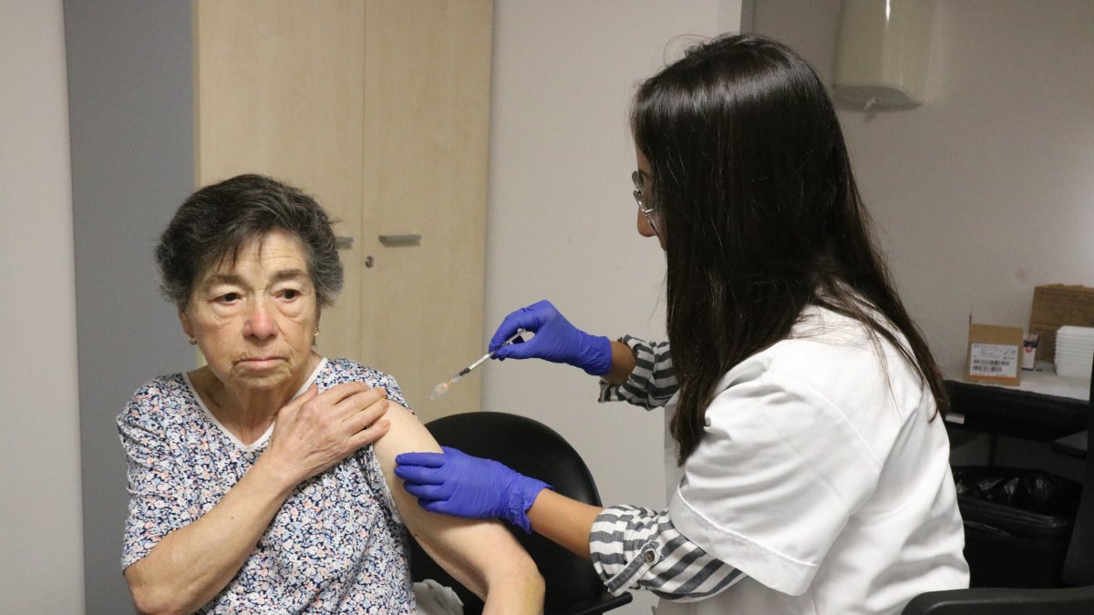 Imatge d’arxiu d’una professional vacunant una pacient de la grip i la covid