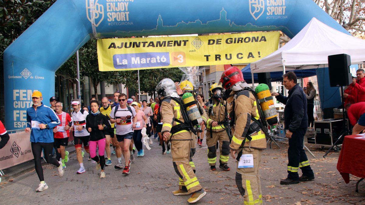Momento que dos parejas de bomberos hacen el relevo, en la Mitja Marató de Girona
