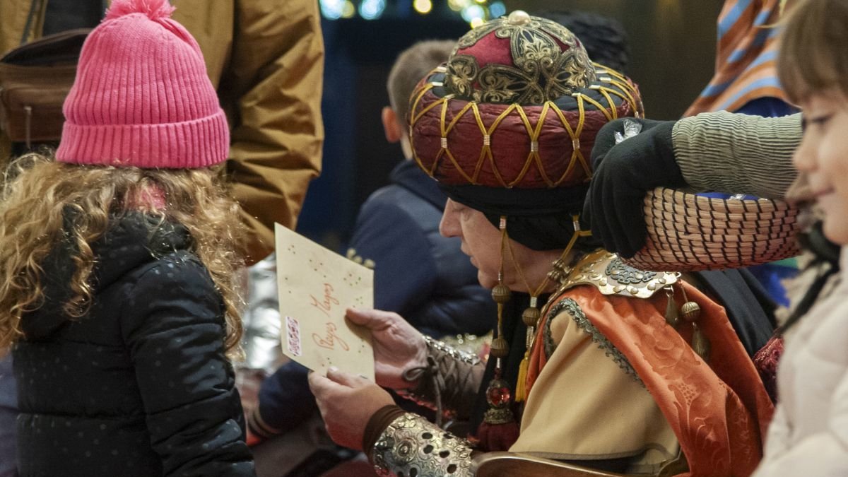 El patge reial del Rei ros recollint la carta d'una nena a la plaça de la Llibertat.