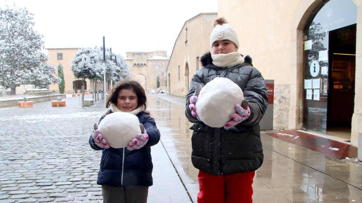 Dos nens mostren les boles de neu que han fet al monestir de Poblet.
