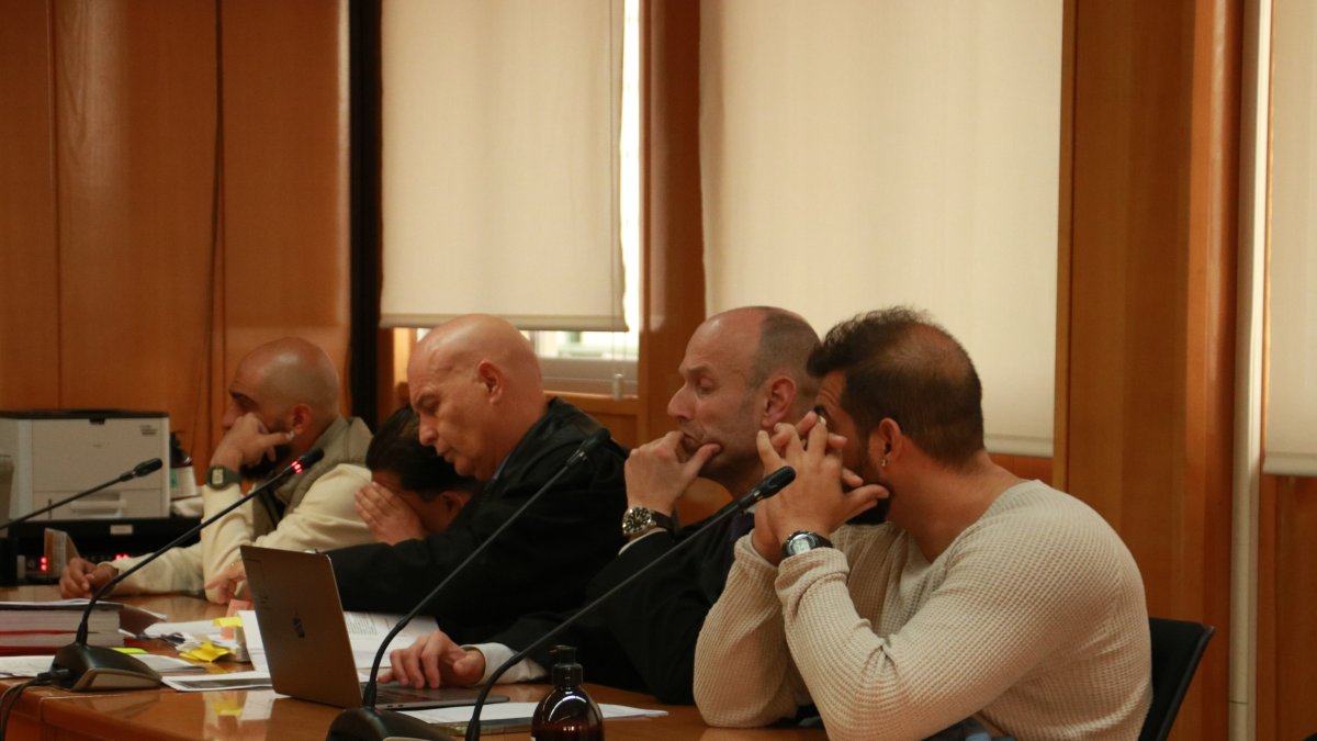 Tres dels cinc homes acusats de diversos delictes, entre ells d'homicidi en grau de temptativa, i els seus advocats, a l'inici del judici.