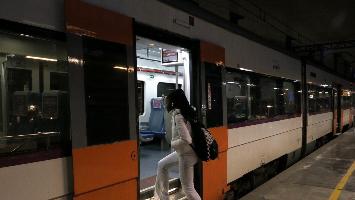 Una viatgera puja a un tren de la RL3 a l'estació de Lleida-Pirineus.