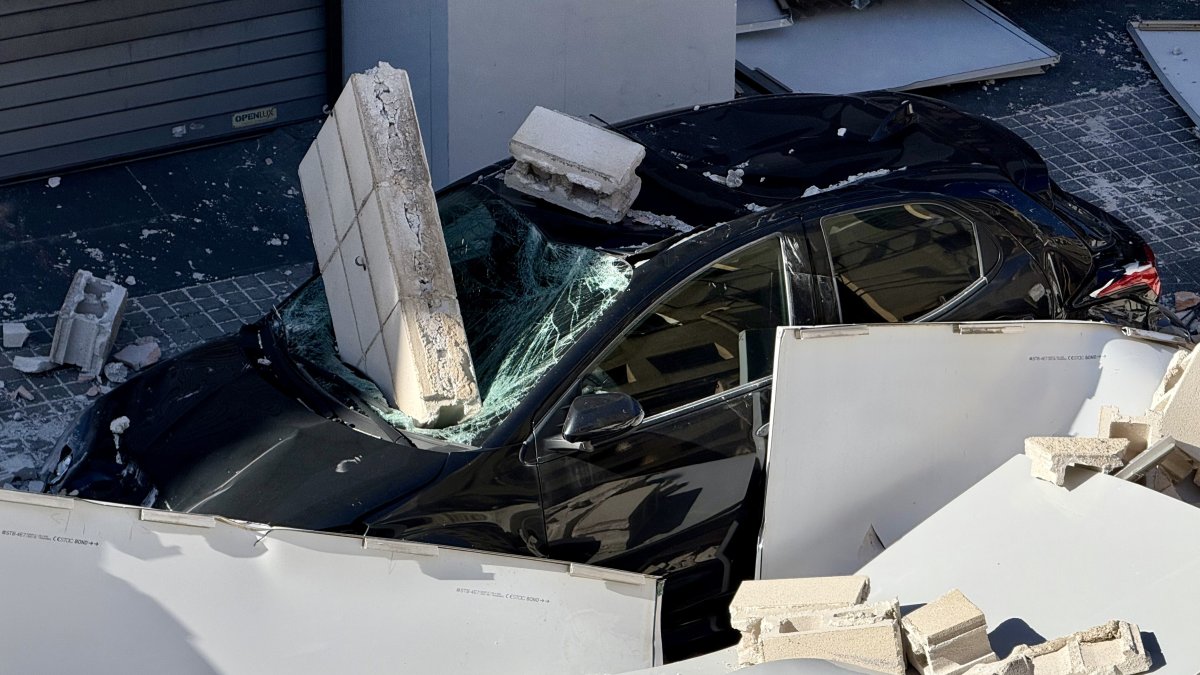Coche donde había la mujer herida leve después de la caída de una cubierta y un muro de un taller en l'Hospitalet de Llobregat.