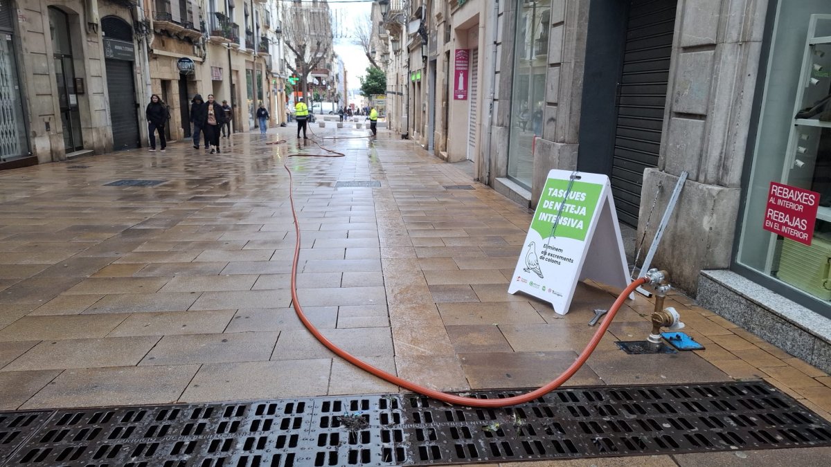 Dos operaris de la brigada eliminant excrements de colom al carrer Comte de Rius.