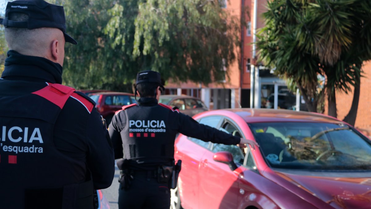 Dos agentes de los Mossos d'Esquadra paran un coche en la entrada del barrio de Sant Josep Obrer de Reus durante el operativo Kanpai