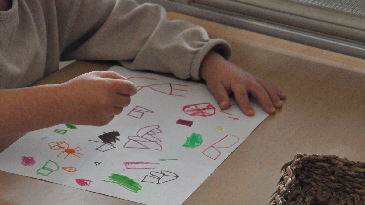 Imatge d'un nen fent un dibuix en una escola.