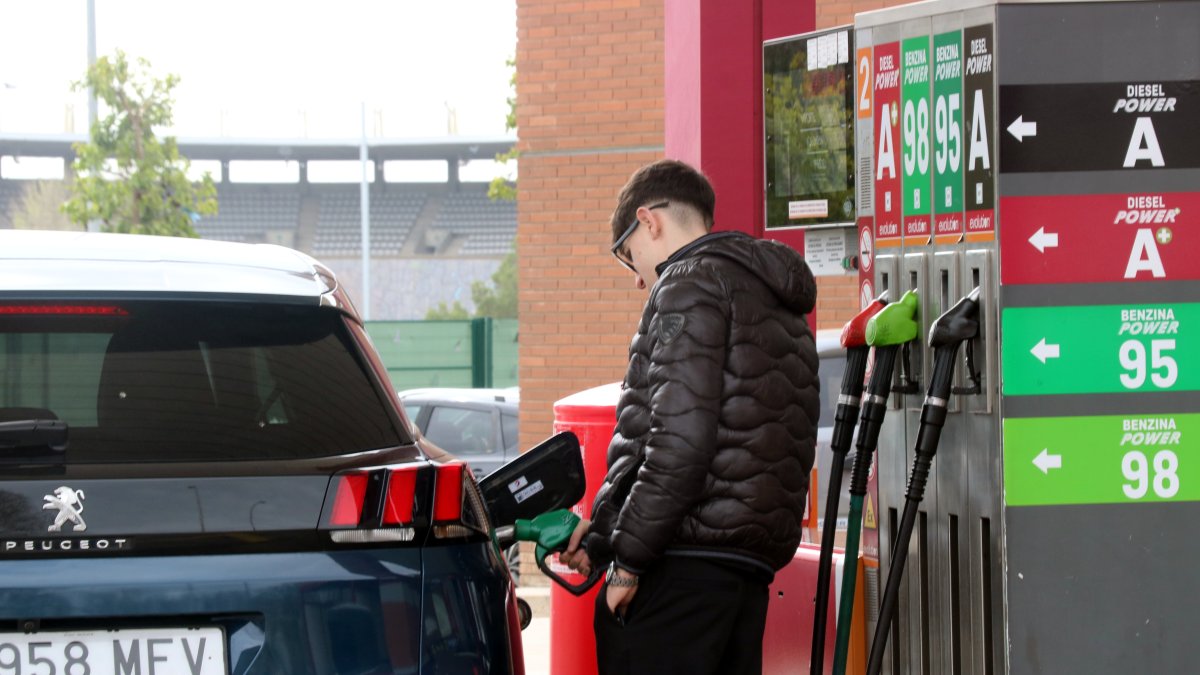Un jove omplint el dipòsit en una gasolinera.