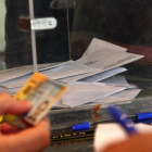 Foto de archivo de una urna y una mano que comprueba el DNI para poder votar.