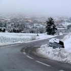 Paisatge nevat a Horta de Sant Joan amb un vehicle que ha sortit de la via a l'entrada al poble.