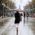 Una dona d'esquenes amb un paraigua caminant per la Rambla de Tarragona.