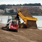 Un camió dipositant arena i una excavadora movent sorra a la platja d'Altafulla.