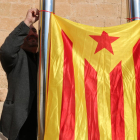 El portaveu d'Alternativa Baix Gaià, Lluís Suñé, penja una estelada entre dos pals de l'Ajuntament de Torredembarra.