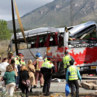 Efectius dels Bombers i Mossos observant l'autobús accidentat un cop la grua l'ha aixecat