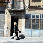 Pla obert del portal de l'immoble on s'ha produït l'homicidi, amb una dona caminant pel davant. Imatge del 24 d'abril del 2016