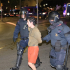 Plano medio de dos agentes y un manifestante detenido en la fuente del Centenari de Tarragona durante los disturbios en la ciudad.