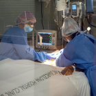 Dos profesionales sanitarias del Hospital Clínico con un paciente ingresado al área de Cuidados intensivos durante la quinta ola de la pandemia de la covid-19 en Cataluña.