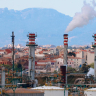 Chimeneas de la industria química de Tarragona humeante y, en el fondo, viviendas de los pueblos del Morell y la Pobla de Mafumet.