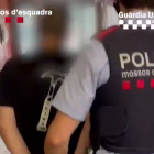 Un agente de Mossos llevado-se uno de los detenidos.