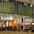 Pantalla indicant un retard en un vol de Ryanair a Frankfurt i cues de fons a l'Aeroport de Reus.