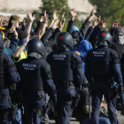 Participantes del corte de la AP-7 en Vandellòs levantan las manos mientras agentes de los antidisturbios de los Mossos D'Esquadra pasan por delante de ellos.