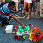 Pla sencer d'un home encenent una espelma a l'ofrena floral del centre de les Rambles el 18 d'agost de 2017