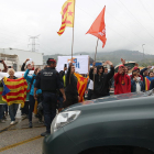 Un vehículo de la Guardia Civil marchándose de la imprenta de Sant Feliu de Llobregat mientras manifestantes independentistas exhiben esteladas y les dicen adiós con la mano.