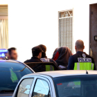 Agentes de la policía española se llevan a una de las personas detenidas después del cacheo de una casa a la calle Cánovas d'Amposta.
