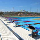 Plano abierto de la piscina de los Juegos Mediterráneos de Tarragona 2018, con operarios trabajando y los saltadores en primer término.