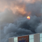 Una columna de fum espès i negre tapa el sol per sobre de la nau del Grup Balfegó en ple incendi.
