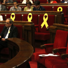 Un lazo amarillo en la bancada del Gobierno tumbado, con el presidente de la Generalitat, Quim Torra, de fondo, y con otros lazos de fondo.