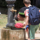 Un jove refrescant-se a una font a Barcelona.