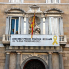 Part central de la façana del Palau de la Generalitat amb la pancarta amb el llaç groc penjats.