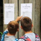 Dos niños observando la lista de alumnos por aula en la entrada de la escuela de Ferreries.