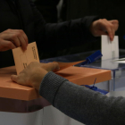 Pla detall d'una mà dipositant les paperetes de les eleccions al Congrés dels diputats i al Senat en una urna.