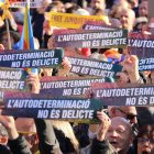 Un grupo de manifestantes sostienen carteles que dicen 'La autodeterminación no es delito' a la manifestación contra el juicio del 1-O en Barcelona.